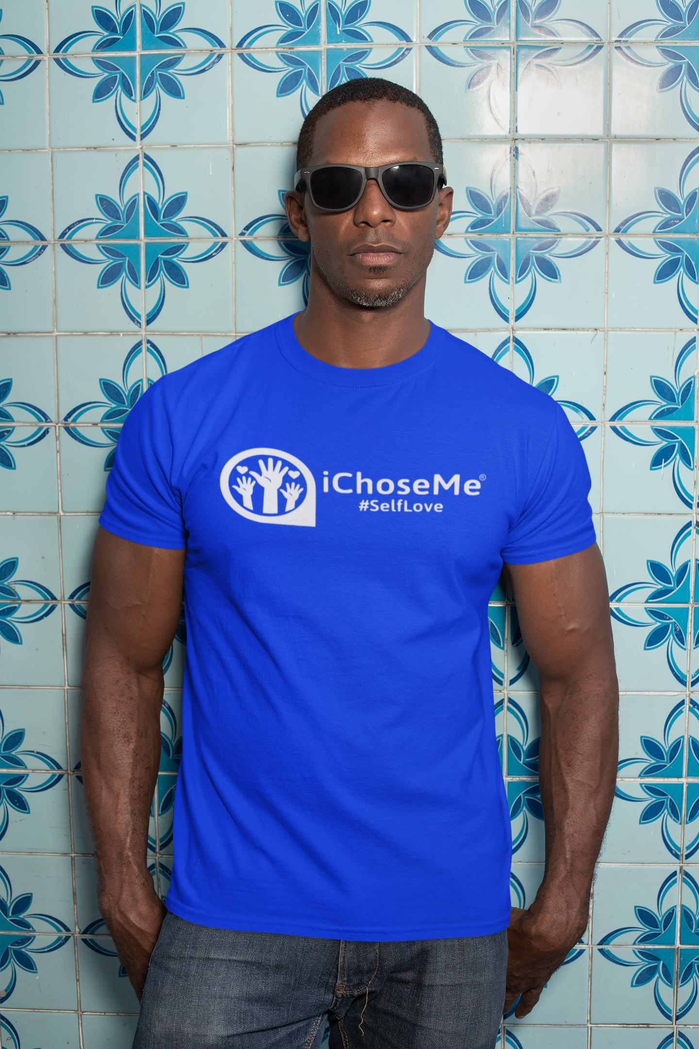 Man wearing a blue iChoseMe self love graphic t shirt and sunglasses against decorative tile wall