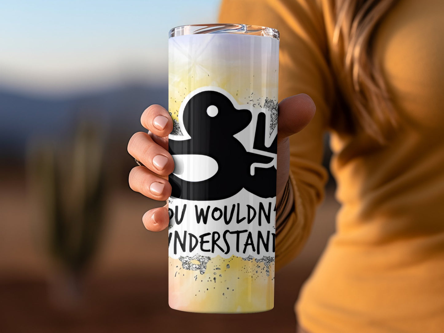 Funny duck tumbler gift with black duck design held by a person in mustard sweater outdoors