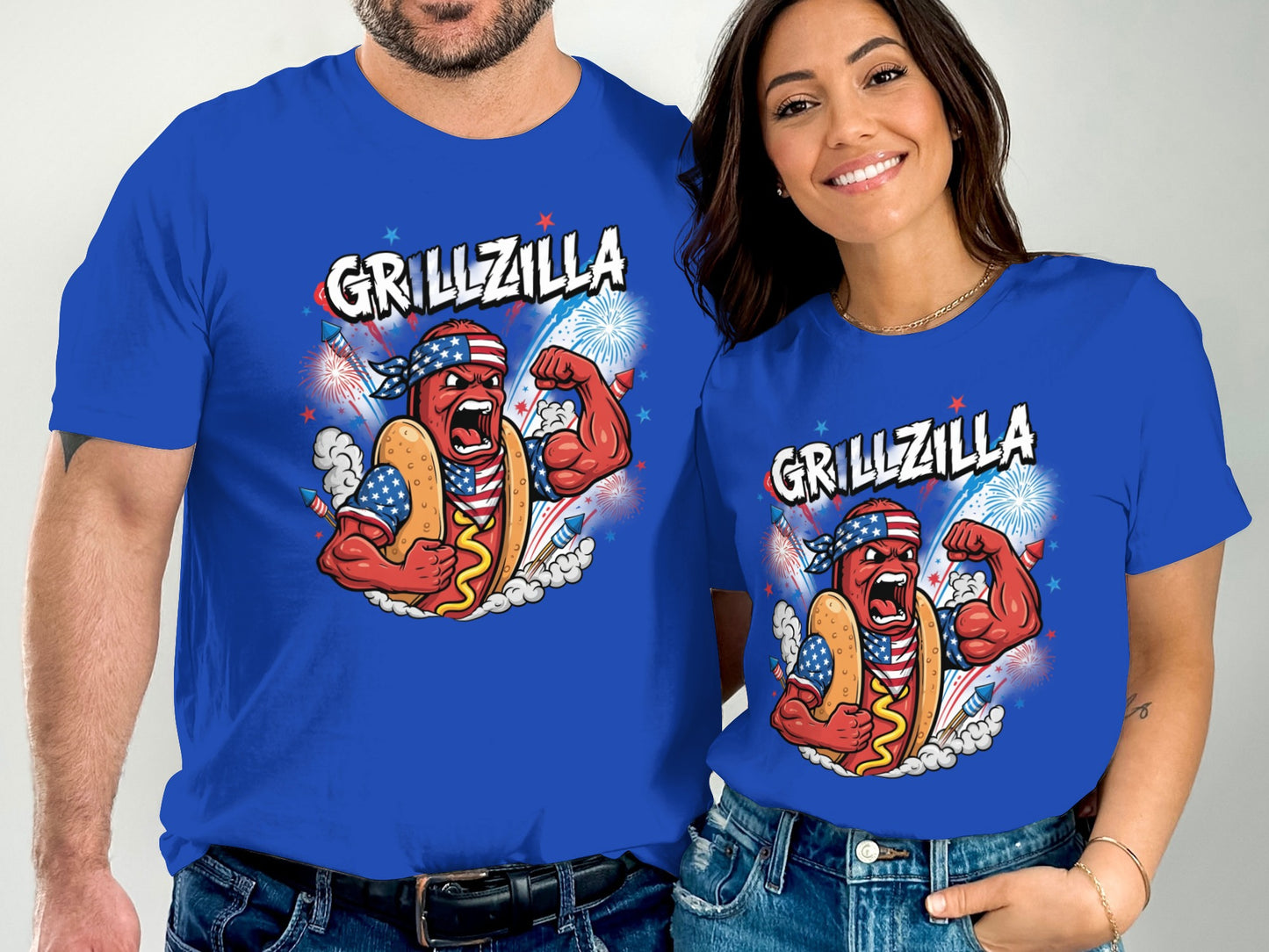 Couple in matching "Grillzilla" hot dog t-shirts celebrating with fireworks.