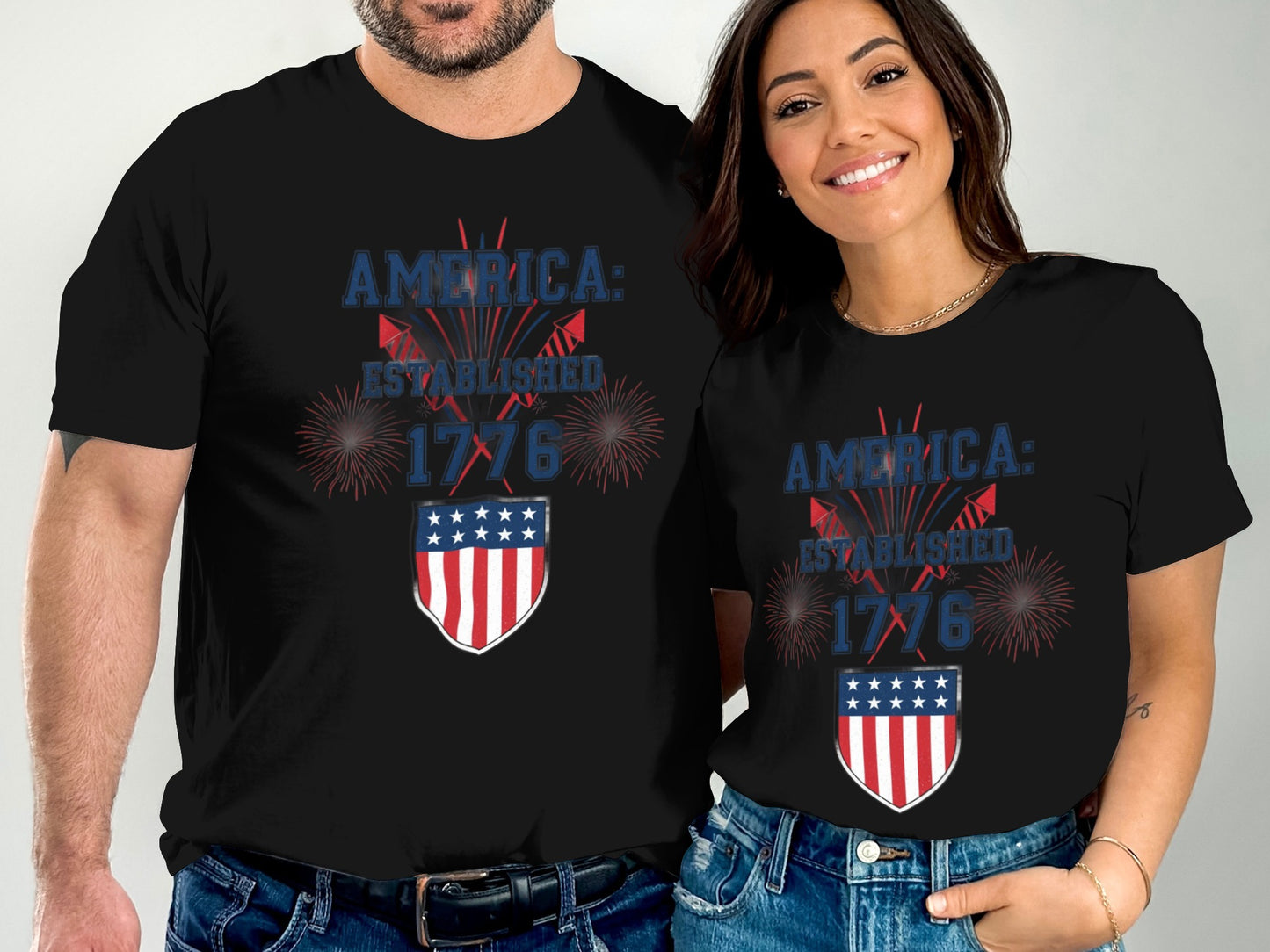 Couple in matching black t-shirts with American flag shield and "America: Established 1776".