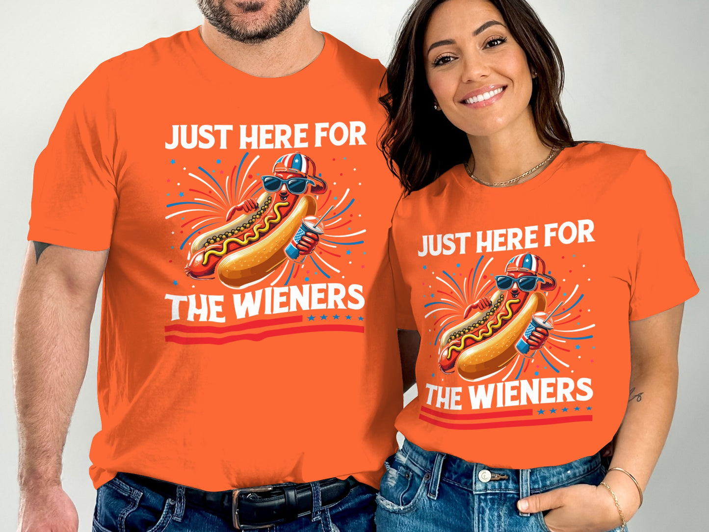 Couple wearing matching orange t-shirts with hot dog graphic and text "JUST HERE FOR THE WIENERS".