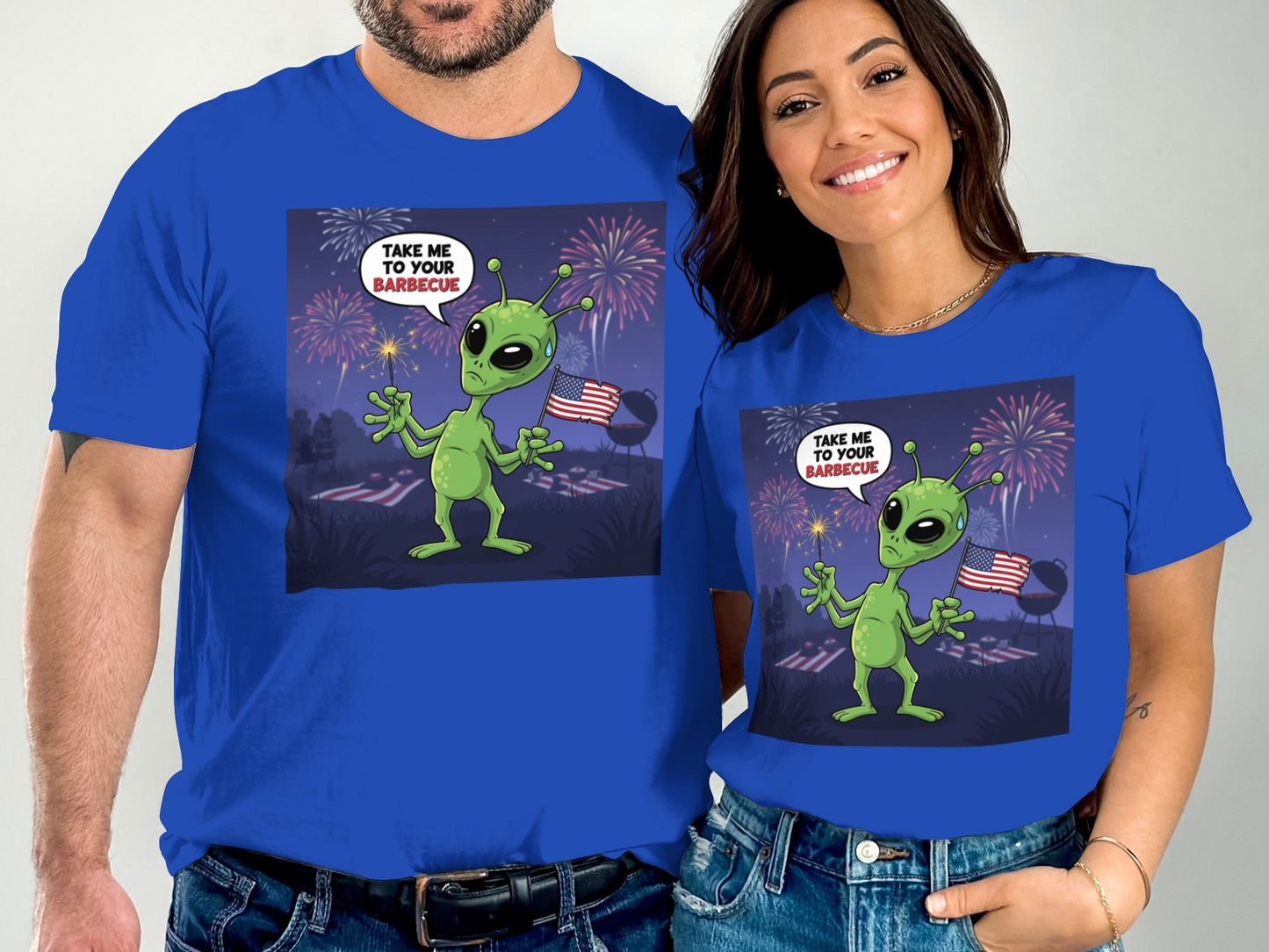Alien on grass with fireworks and American flag, wearing a shirt that says "TAKE ME TO YOUR BARBECUE".