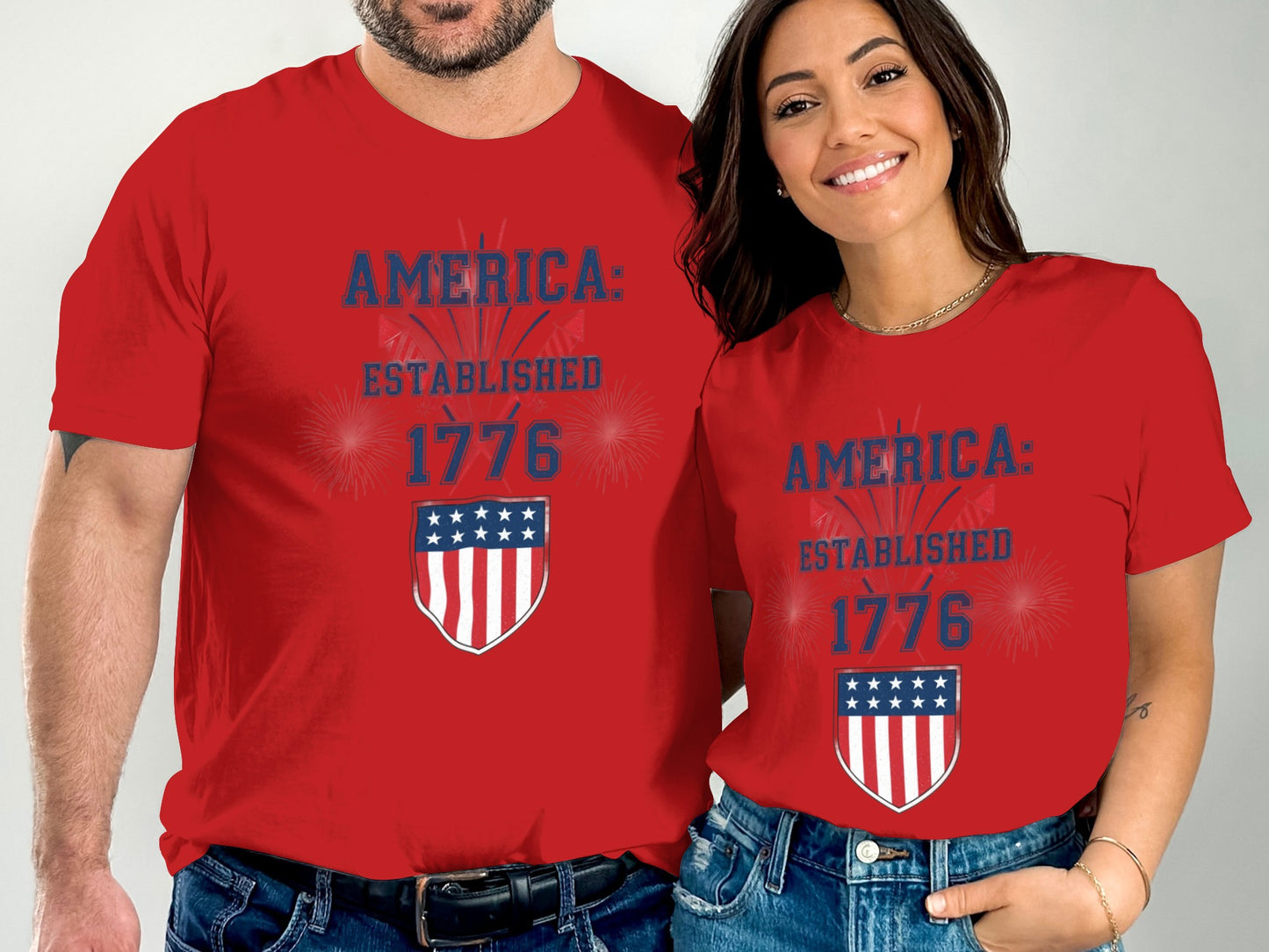 Couple wearing red t-shirts with "AMERICA: ESTABLISHED 1776" and a shield.