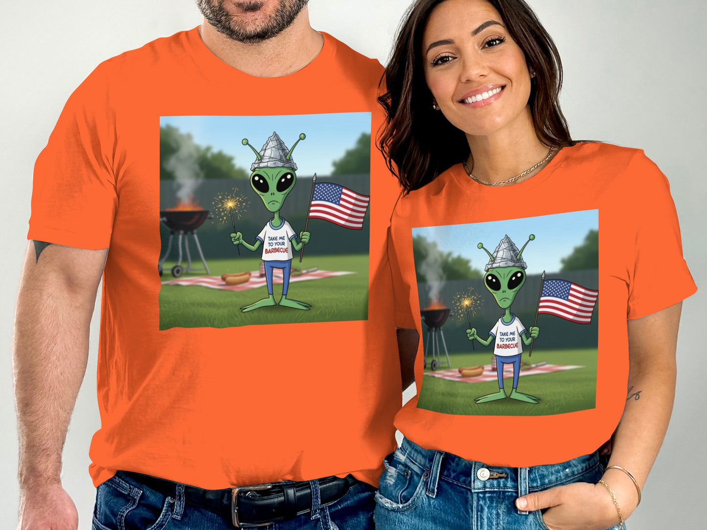 Two people in orange t-shirts featuring an alien with an American flag.