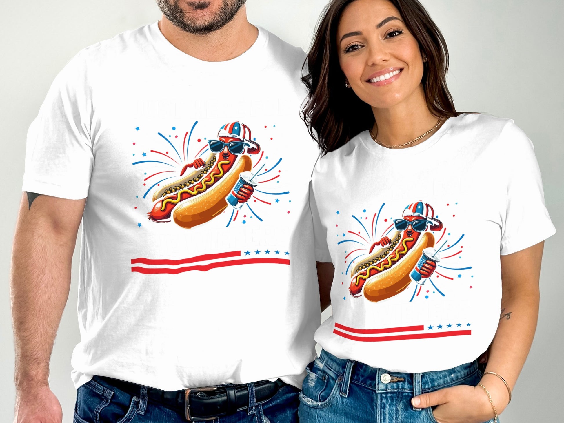 Two people wear matching white t-shirts with a hot dog graphic and fireworks.