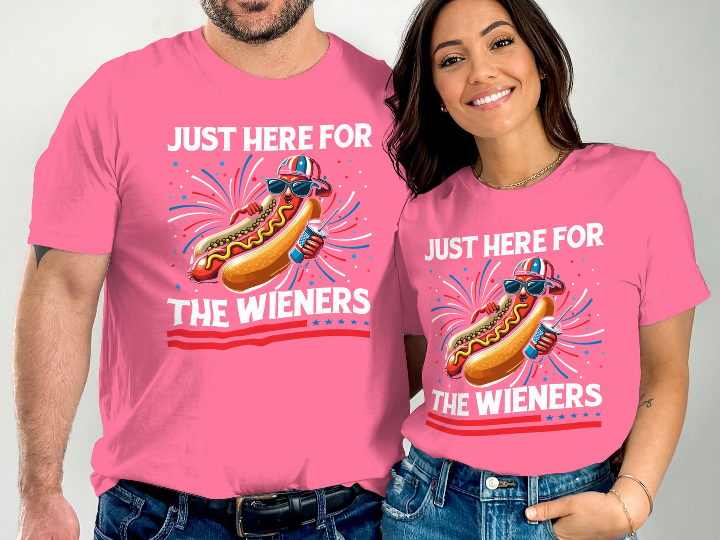 Couple wearing pink t-shirts with "Just Here For The Wieners" and hot dog graphics.