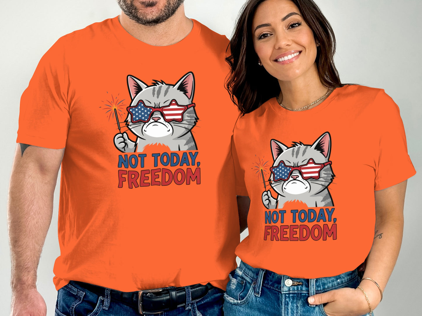 Two people wear orange t-shirts with a cartoon cat wearing sunglasses and holding fireworks.