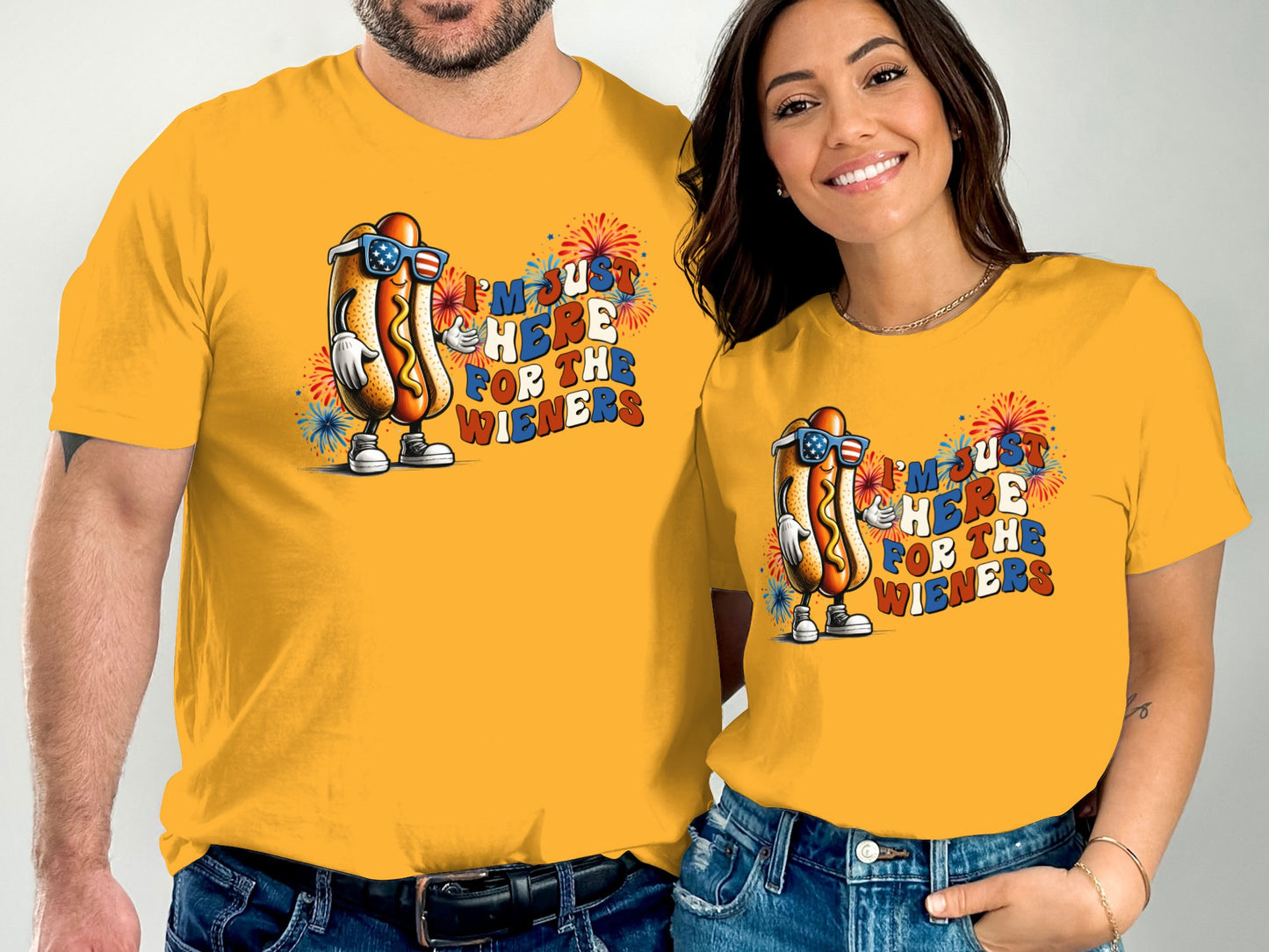 Couple wearing matching yellow t-shirts with a cartoon hot dog and "I'm just here for the wieners" text.