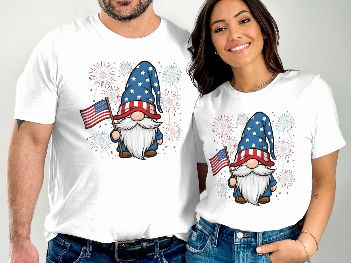 Couple wearing matching white t-shirts with patriotic gnome and fireworks design.