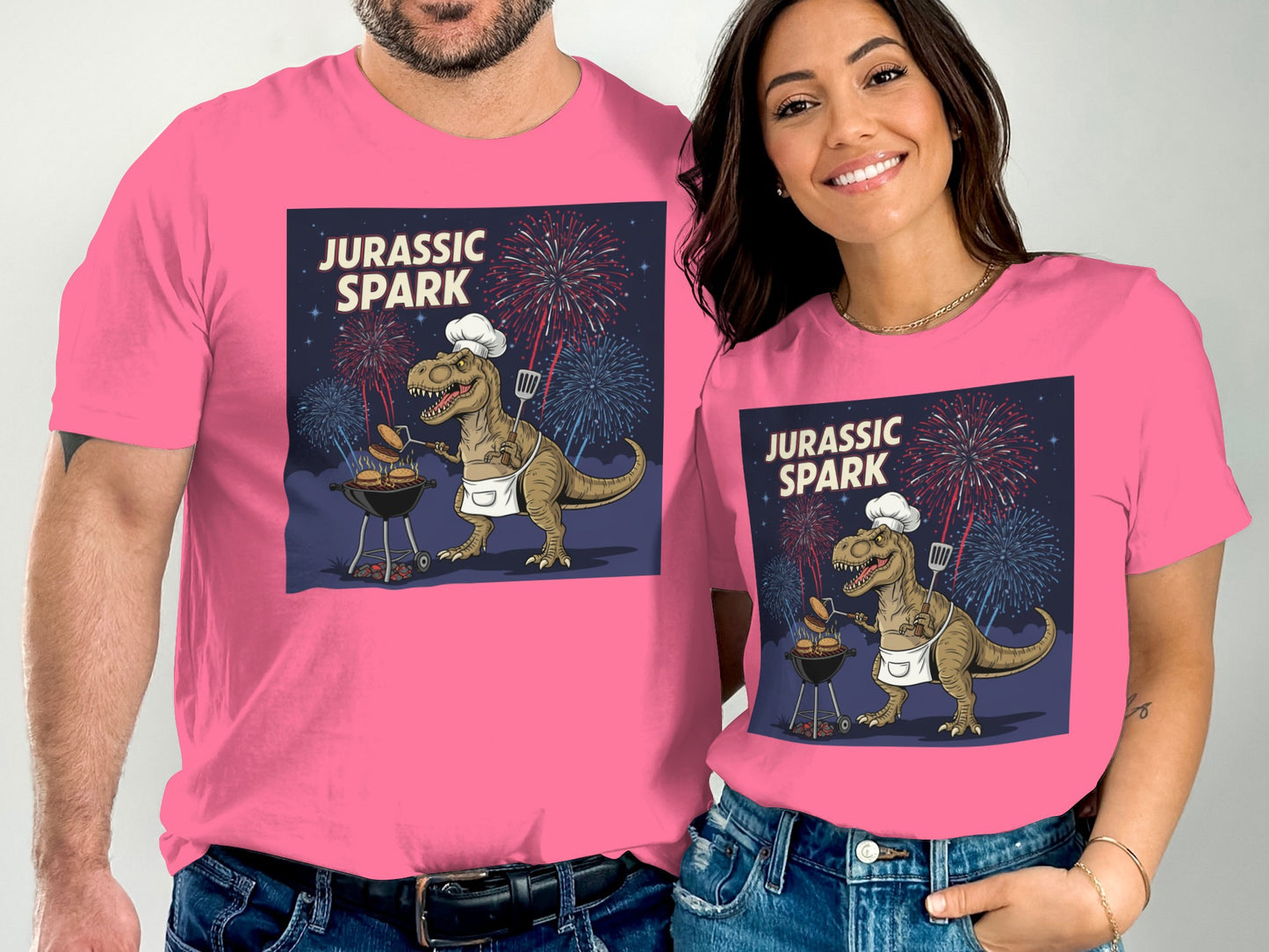 Pink t-shirts featuring a Tyrannosaurus Rex grilling with fireworks.