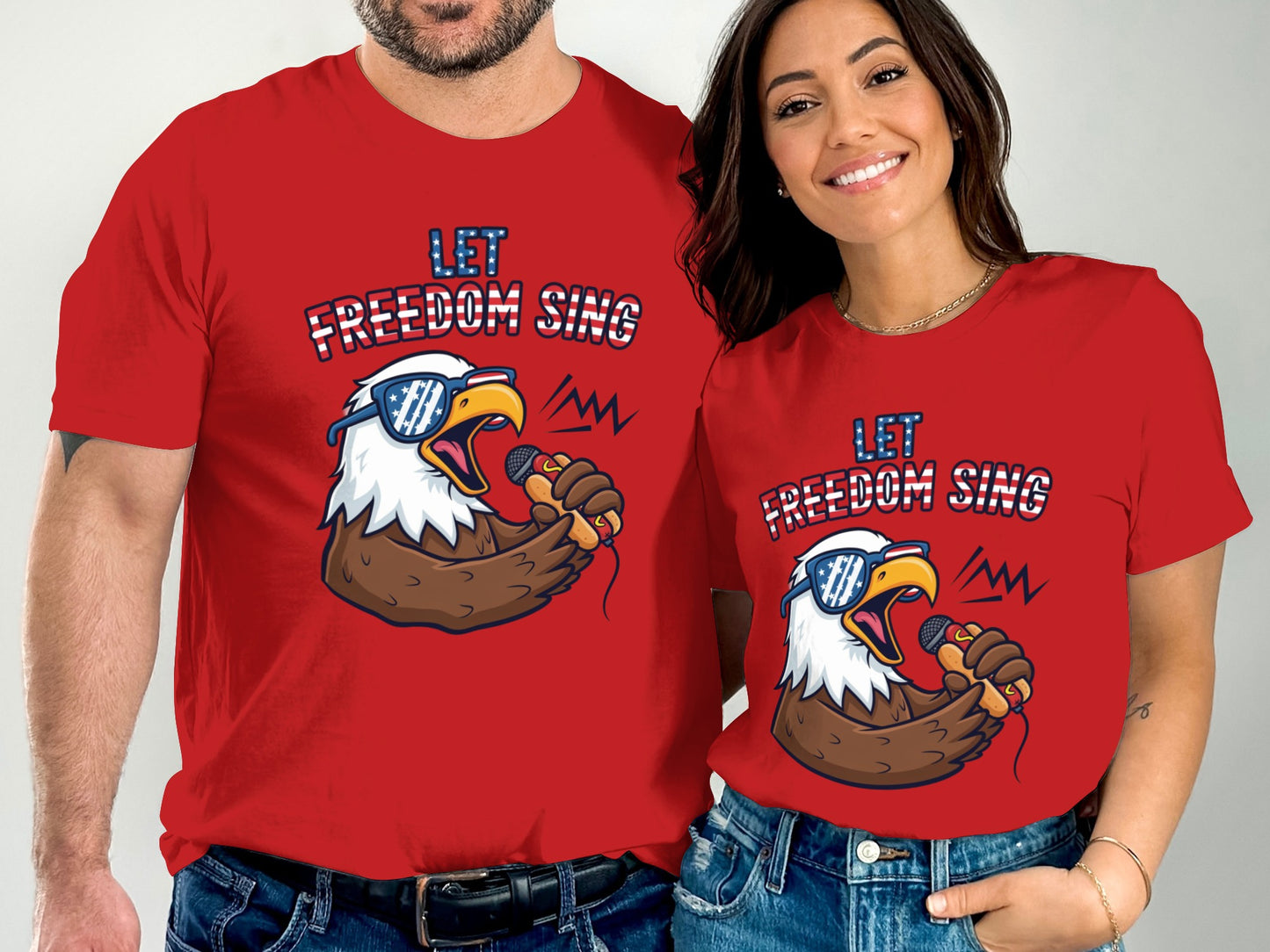 Man and woman wear red t-shirts with an eagle singing and "Let Freedom Sing" text.