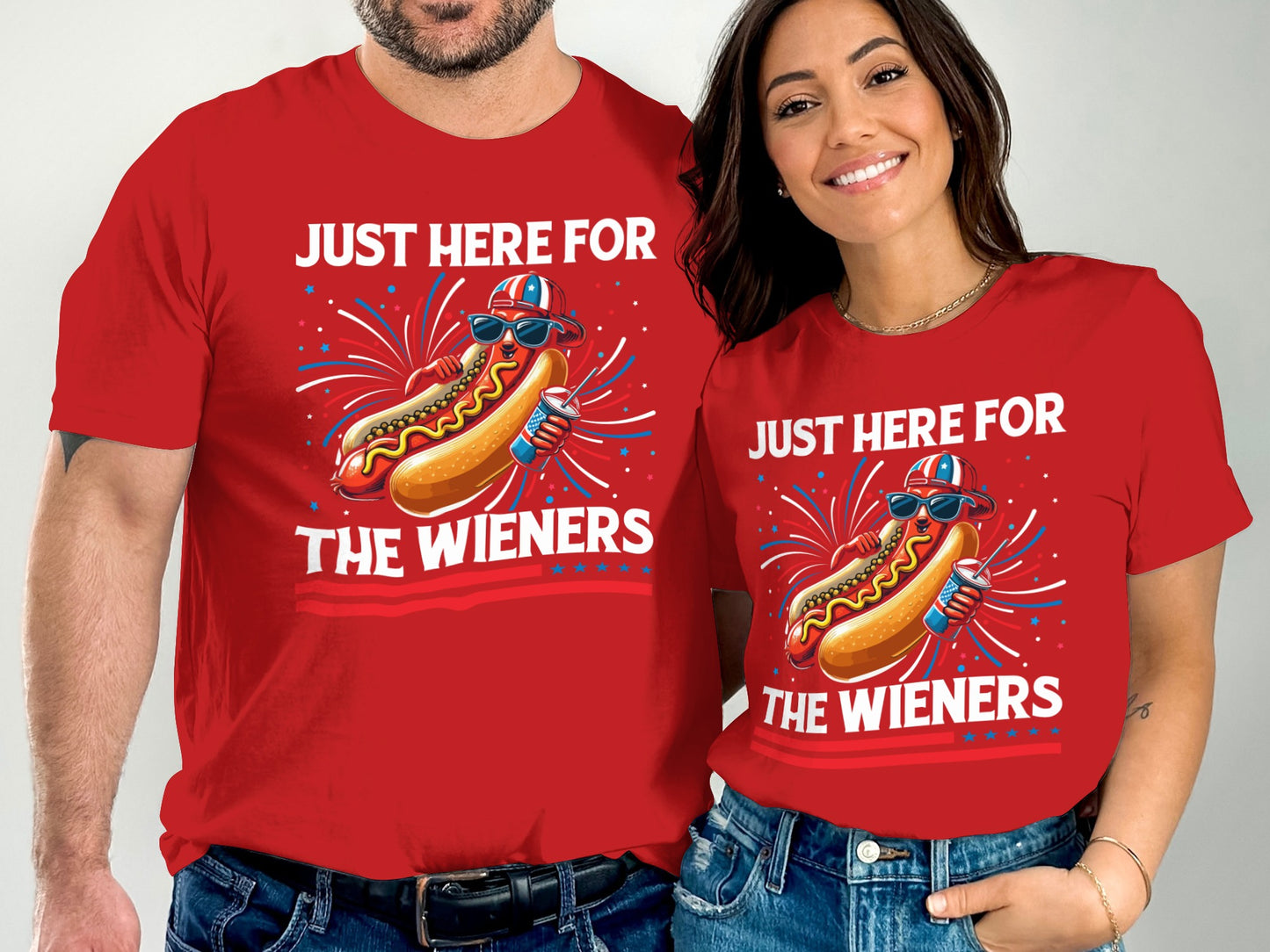 Couple wearing matching red t-shirts with hot dog graphic and "Just Here For The Wieners" text.