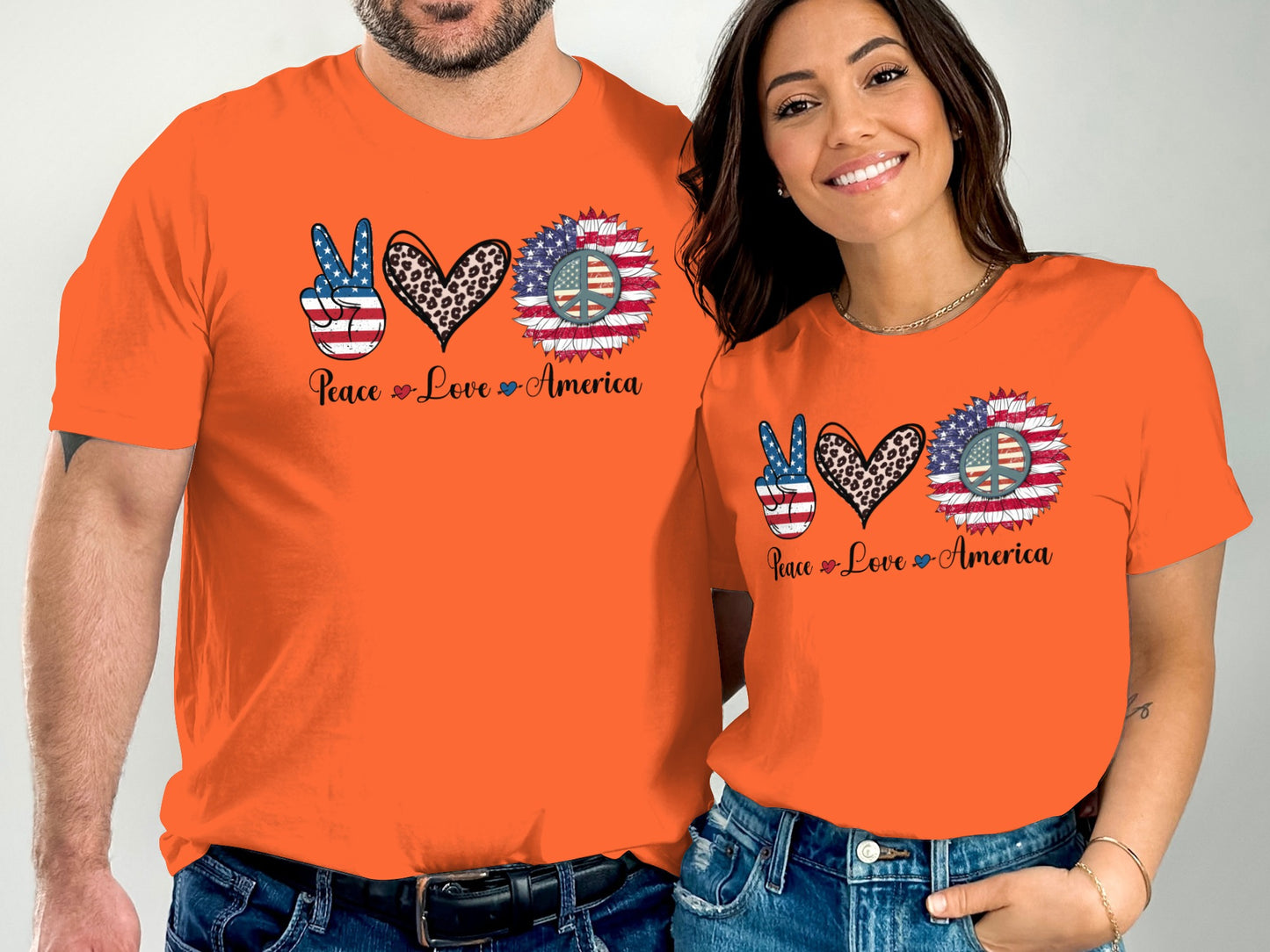 Two people wear orange t-shirts with a peace sign, heart, and sunflower design.
