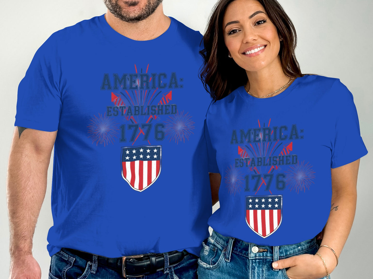Couple wearing matching blue t-shirts with "America: Established 1776" and patriotic shield.