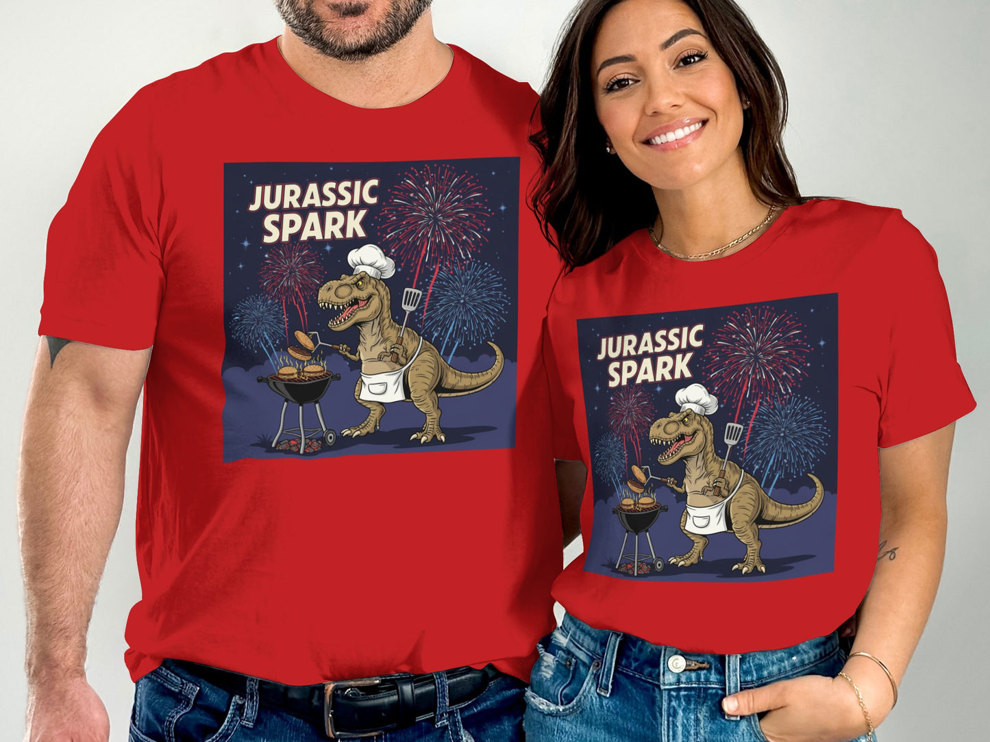 Couple wearing red t-shirts with Jurassic Park dinosaur grilling graphic.