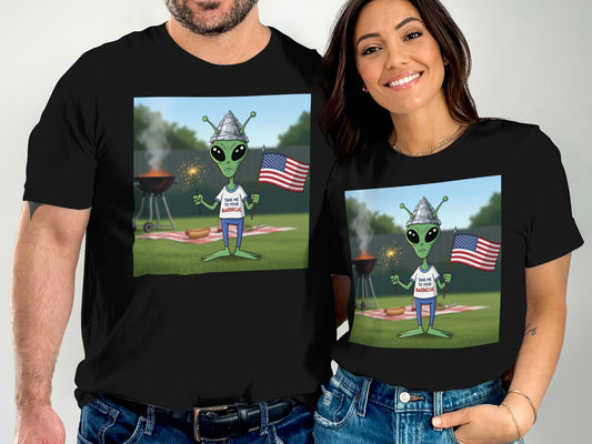 Man and woman wearing matching t-shirts with alien at barbecue graphic.