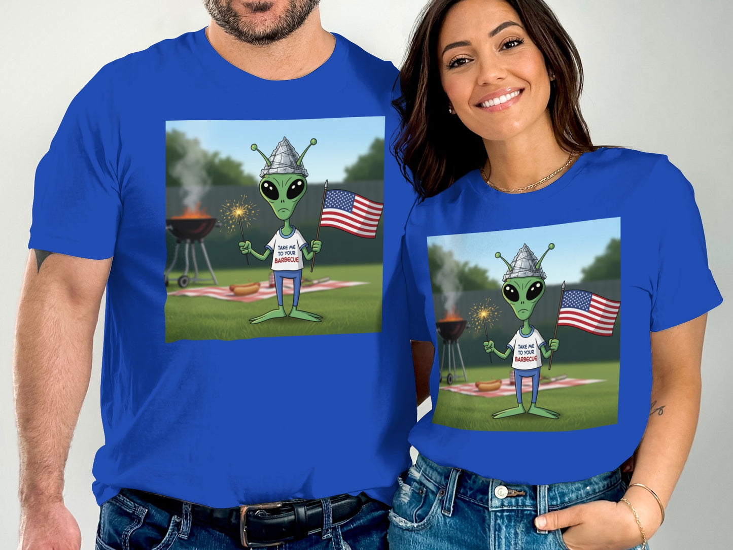 Alien with American flag at barbecue, wearing "Take Me To Your Barbecue" t-shirt.
