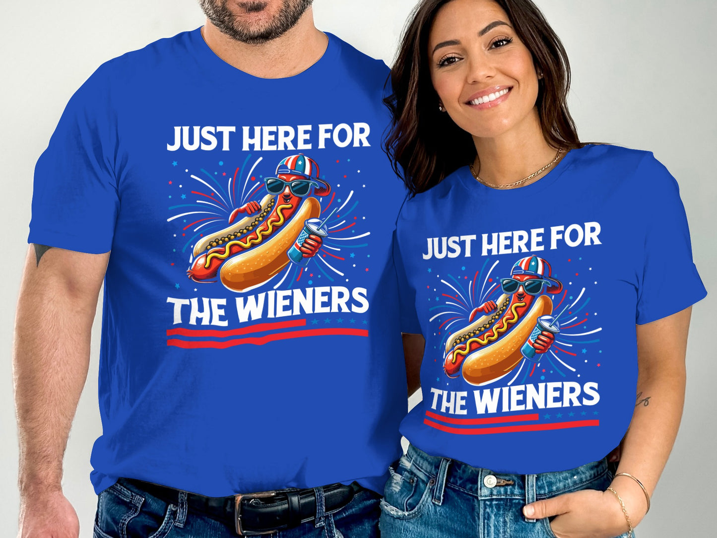 Couple wearing matching blue t-shirts with hot dog graphic and text "JUST HERE FOR THE WIENERS".