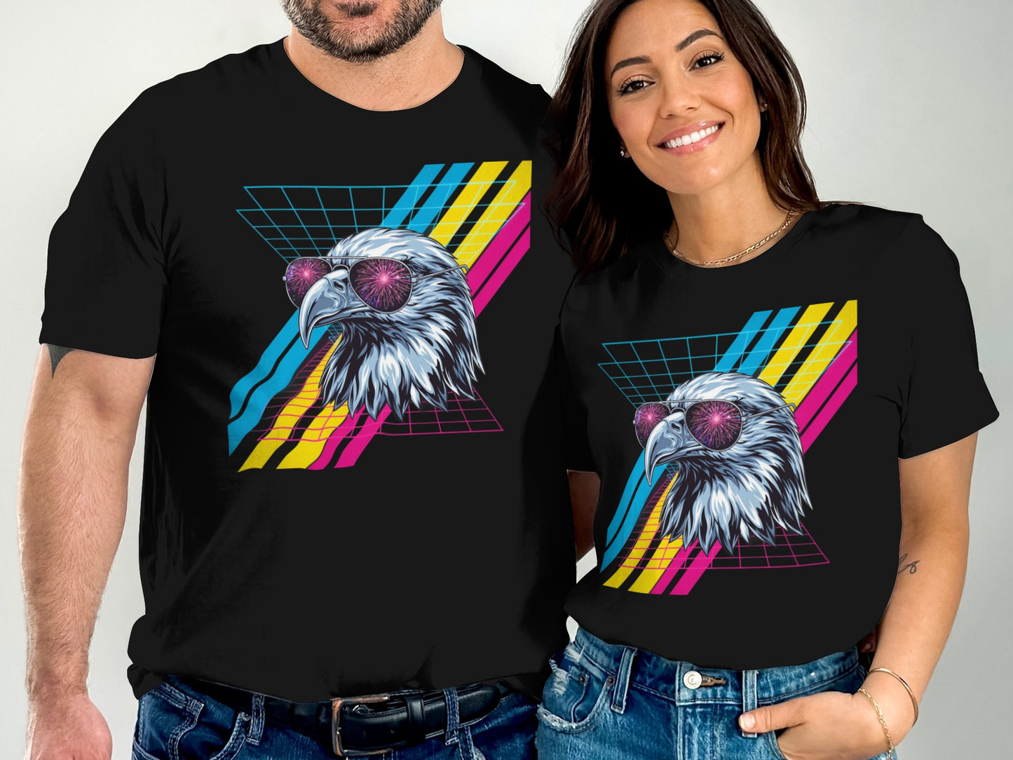 Two people wear black t-shirts featuring an eagle with pink sunglasses and a retro grid pattern.