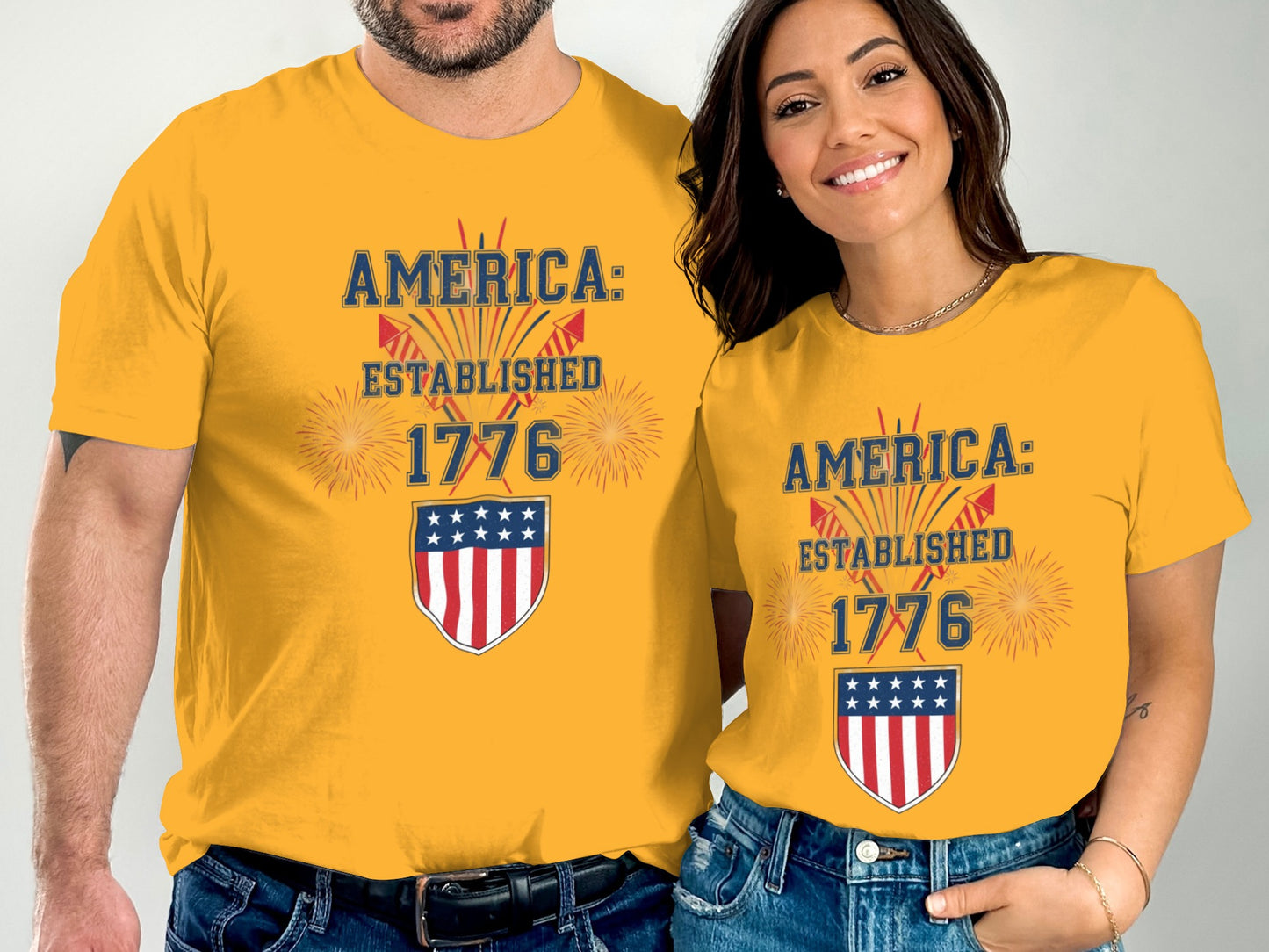 Couple wearing matching yellow t-shirts with "America: Established 1776" and a shield graphic.