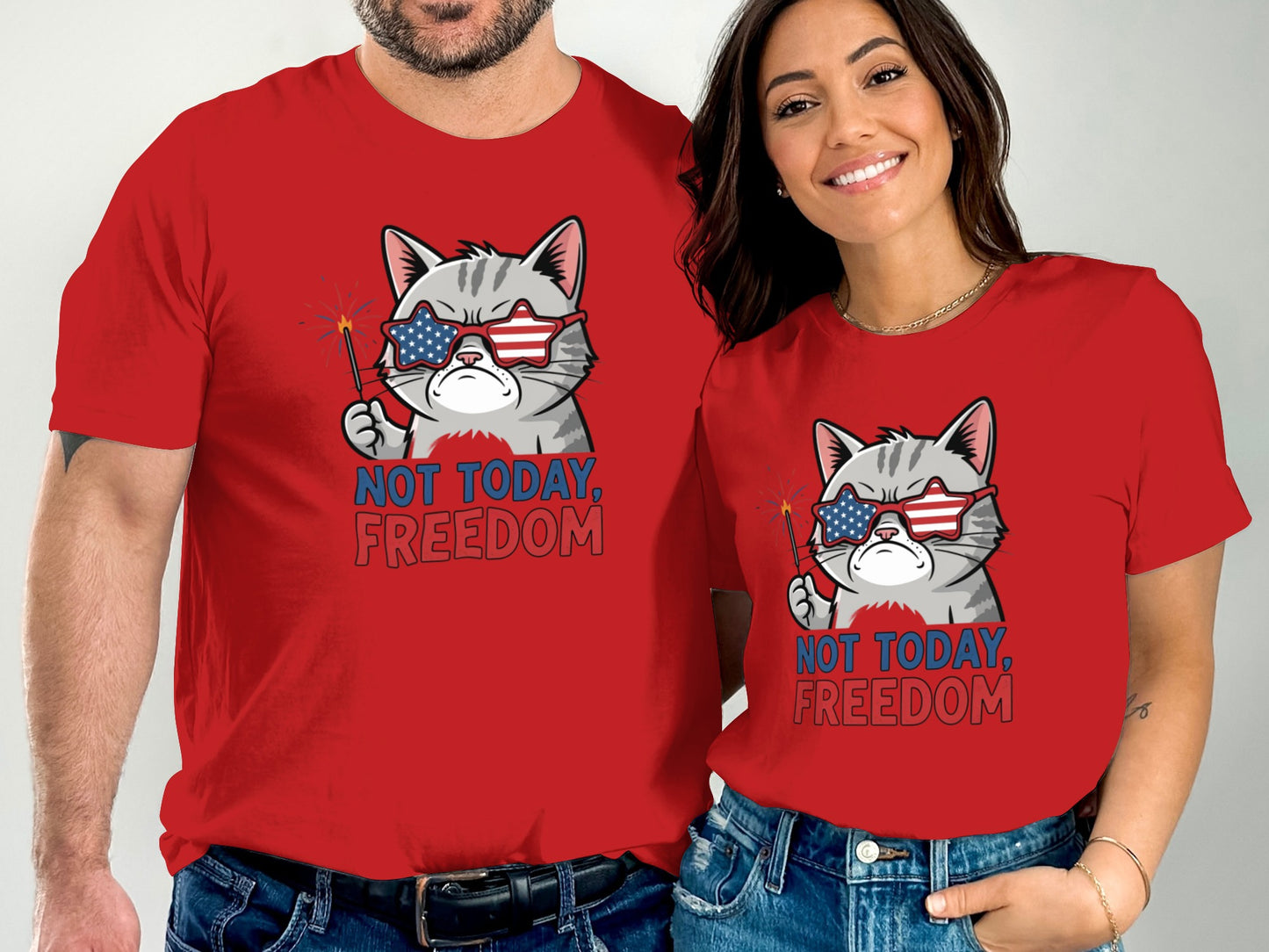 Two people in red t-shirts featuring a cat wearing sunglasses and holding sparklers.