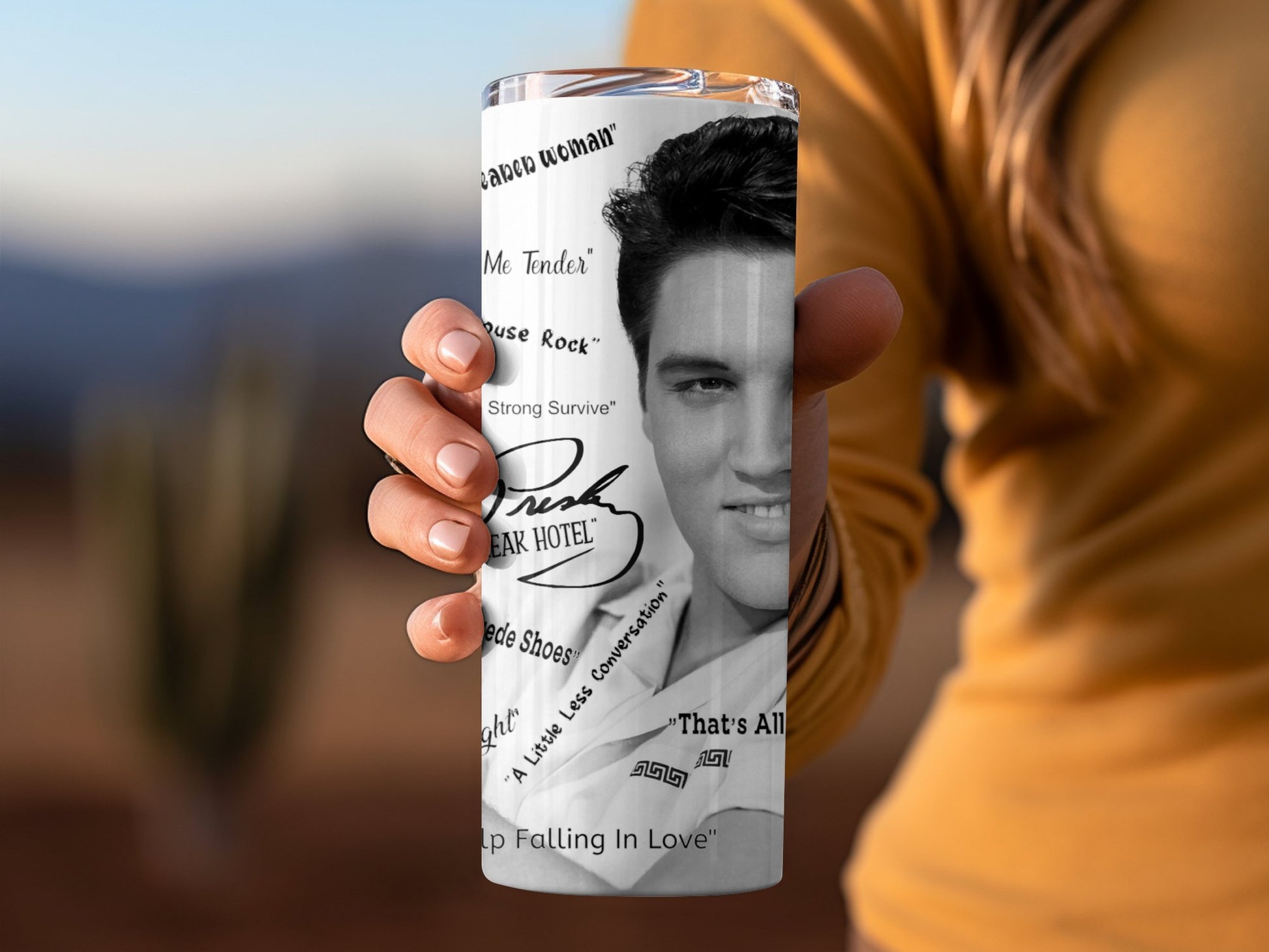 Hand holding Elvis tumbler gift featuring black and white Elvis Presley portrait and song titles