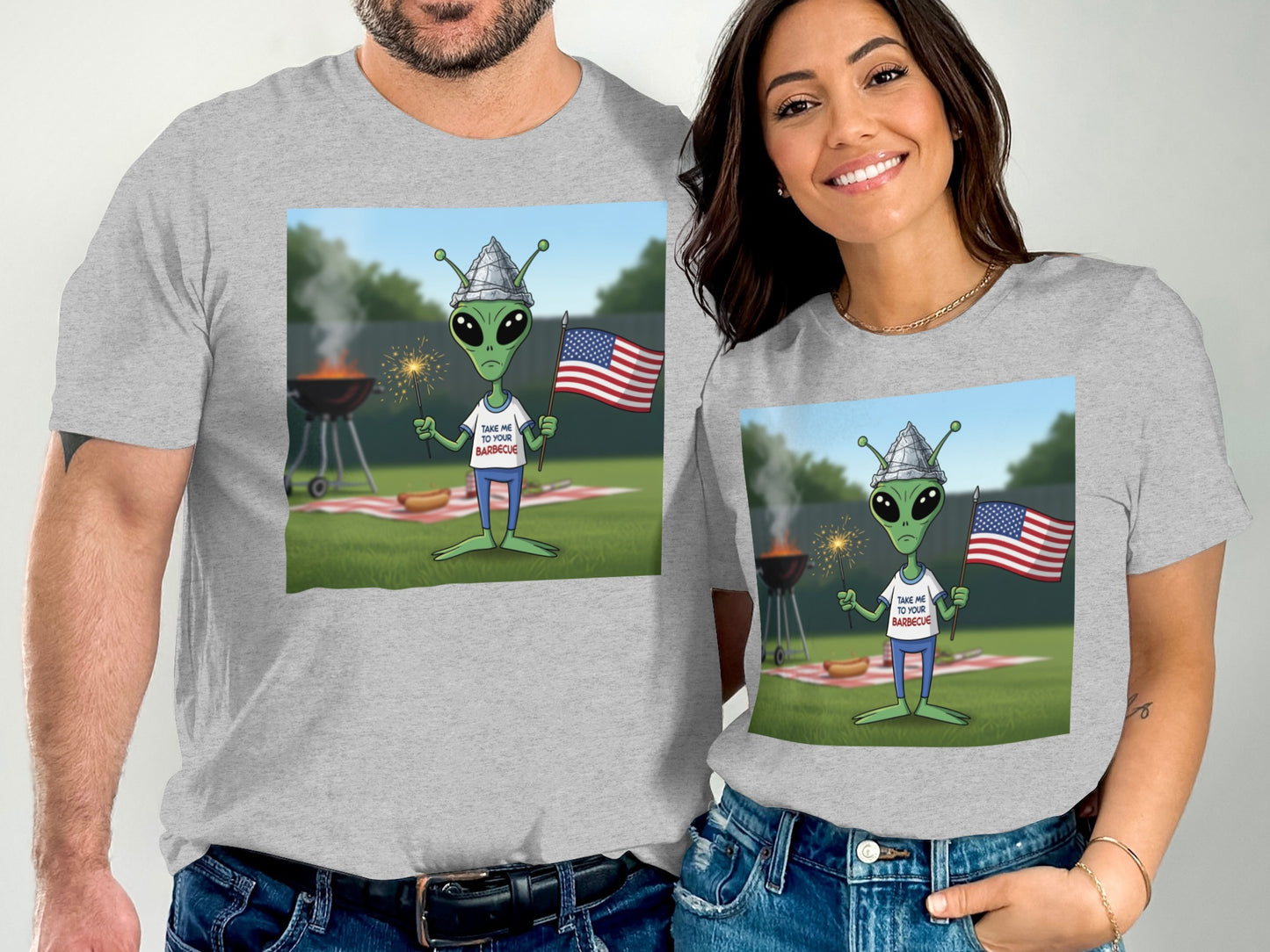 Couple wearing matching gray t-shirts with alien celebrating Independence Day with fireworks.