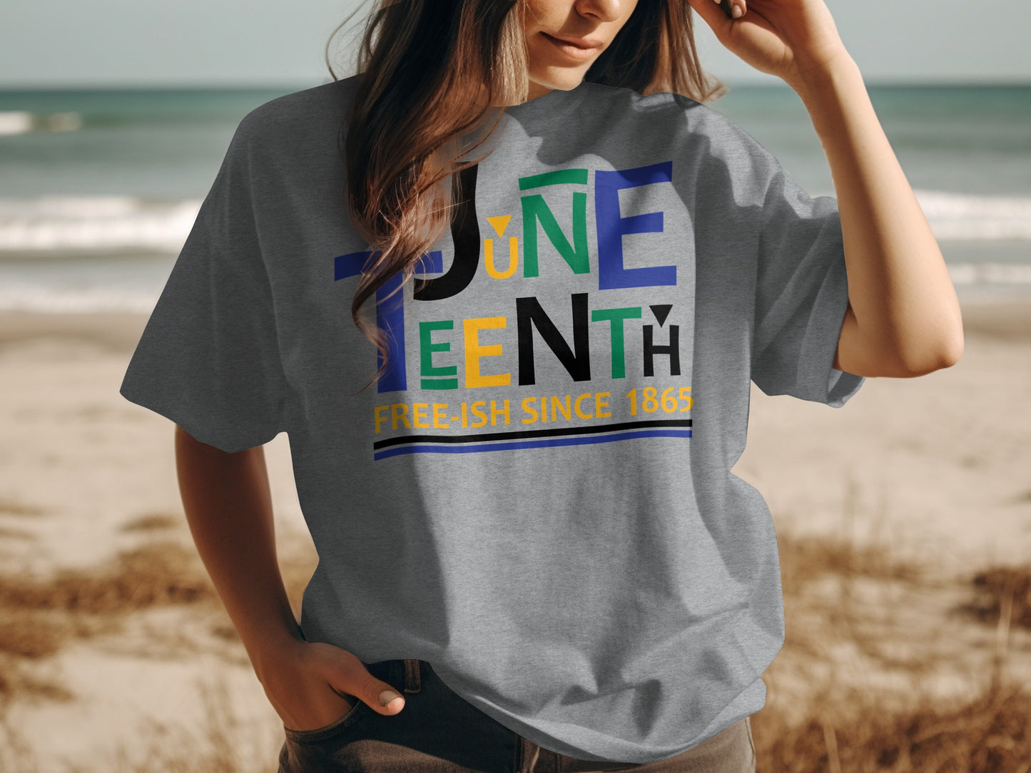 Gray Juneteenth T-Shirt with colorful text design and Free-ish Since 1865 slogan worn at the beach