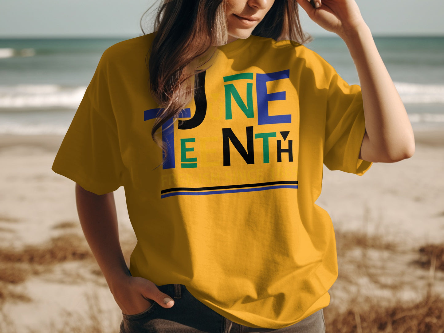 Juneteenth T-Shirt in mustard yellow with colorful block lettering worn by woman at the beach