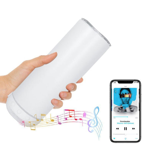 Hand holding white sublimation tumbler with Bluetooth speaker playing music next to smartphone
