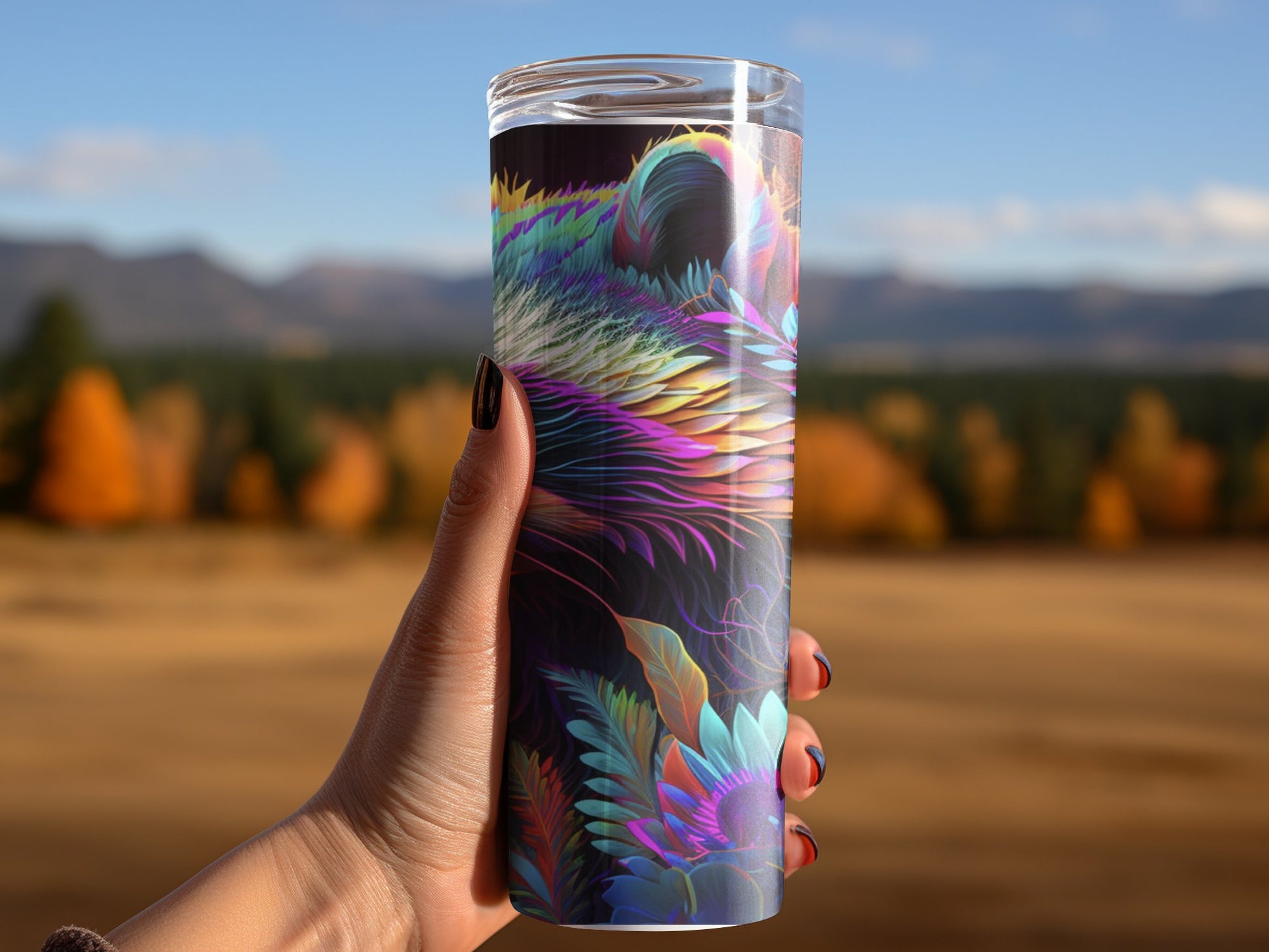 Bates Custom Creations vibrant racoon print tumbler held outdoors with mountains and autumn trees