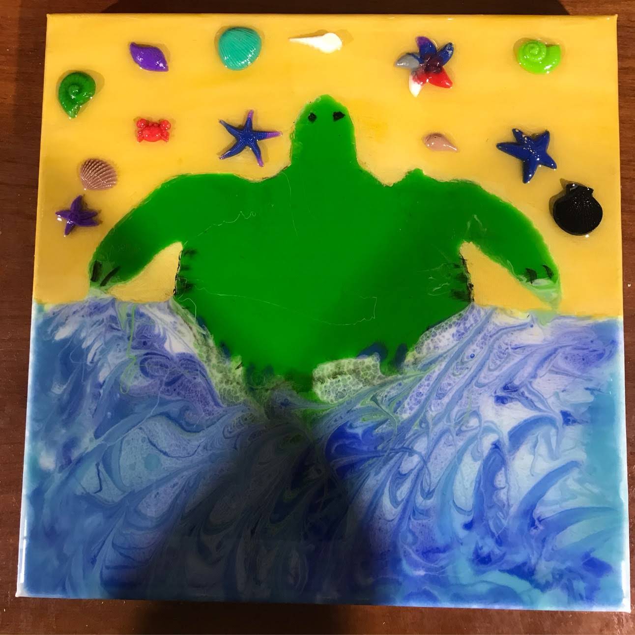 Colorful handcrafted turtle decor featuring a green turtle with sea shells and starfish on a yellow and blue background